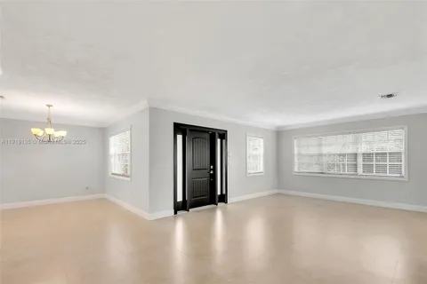 an empty room with chandelier fan and windows