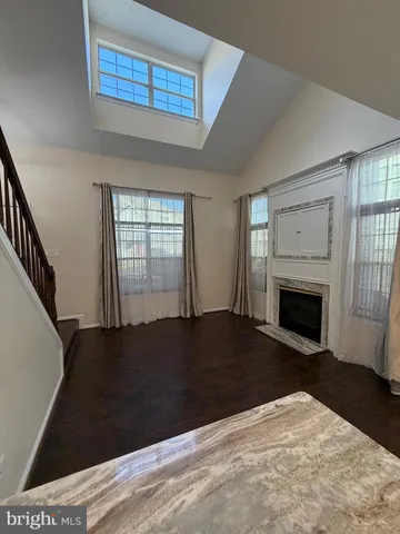 a view of an empty room with wooden floor fireplace and a window