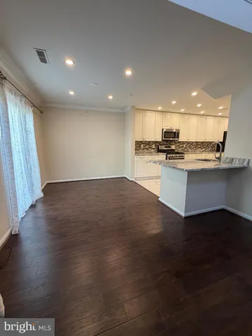 a view of a kitchen with a sink a refrigerator and wooden floor