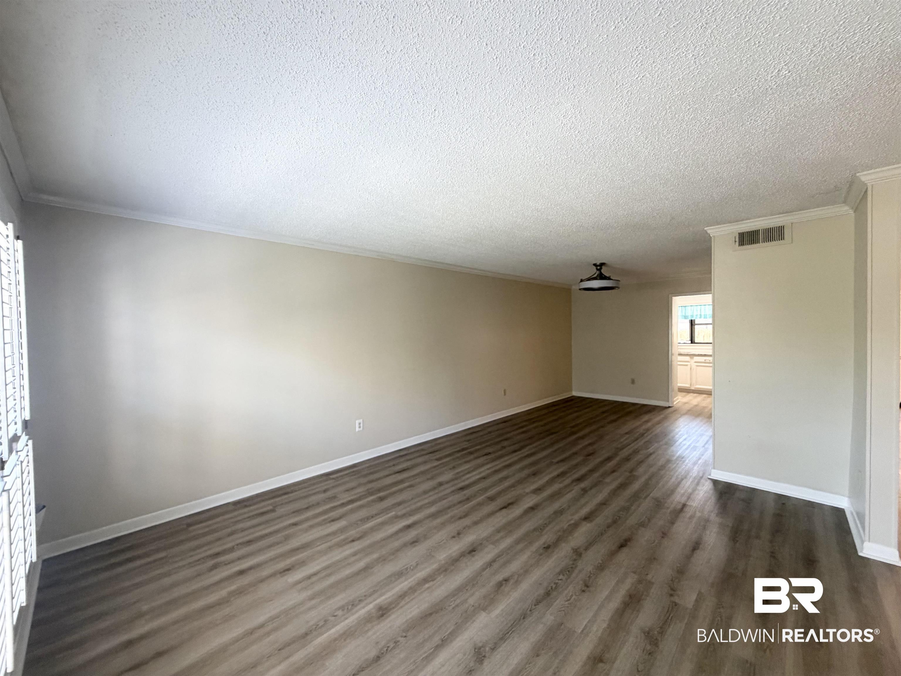 2901 Grant Street, Unit 902 Mobile, AL 36606 - Photo 32 of 35 Unfurnished living room with dark wood-type flooring, a textured ceiling, and ornamental molding