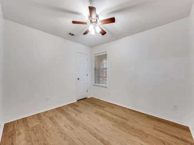 an empty room with wooden floor and ceiling fan