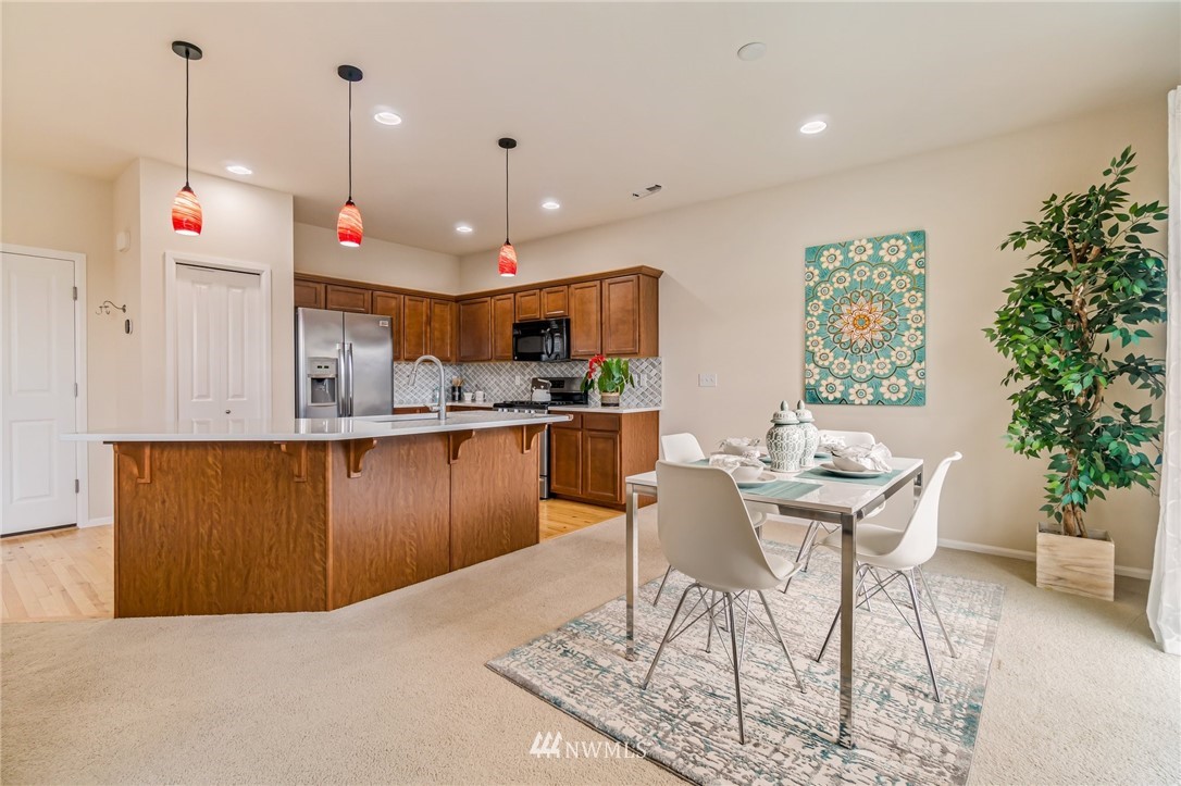 4114 167th Place Southeast Bothell, WA 98012 - Photo 12 of 38 a kitchen with stainless steel appliances kitchen island granite countertop a table chairs and a view of living room