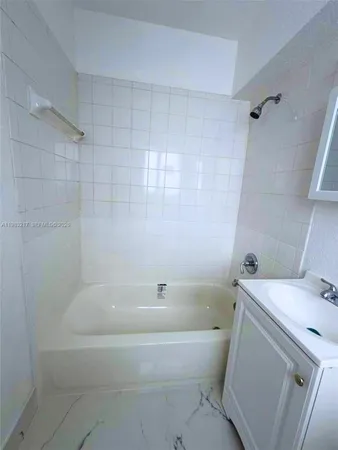 a white bath tub sitting next to a white toilet and vanity