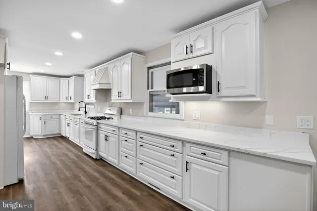 a kitchen with granite countertop a sink a stove a oven a dining table and chairs