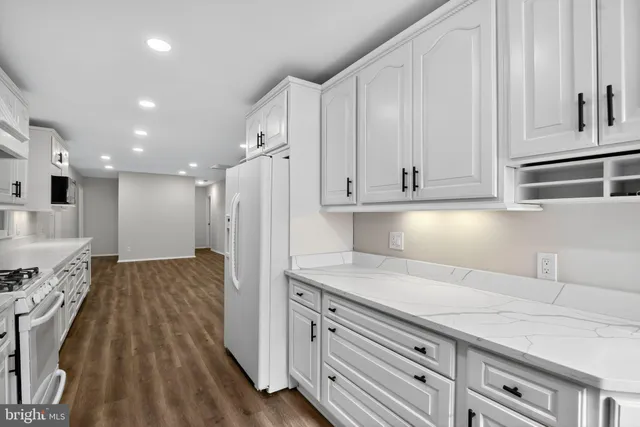 a kitchen with granite countertop white cabinets and stainless steel appliances