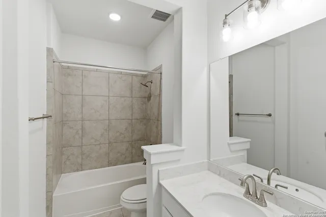 a bathroom with a bathtub shower sink vanity and toilet