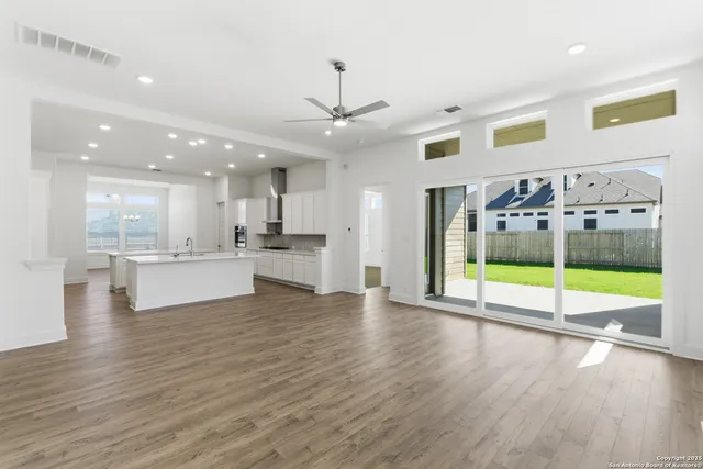 a view of an empty room with kitchen view and a floor to ceiling window