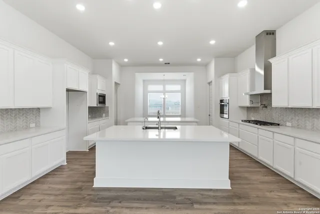 a large kitchen with kitchen island a large counter top and stainless steel appliances