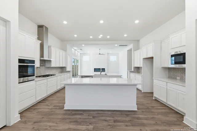 a large kitchen with stainless steel appliances granite countertop a large counter top and a stove top oven