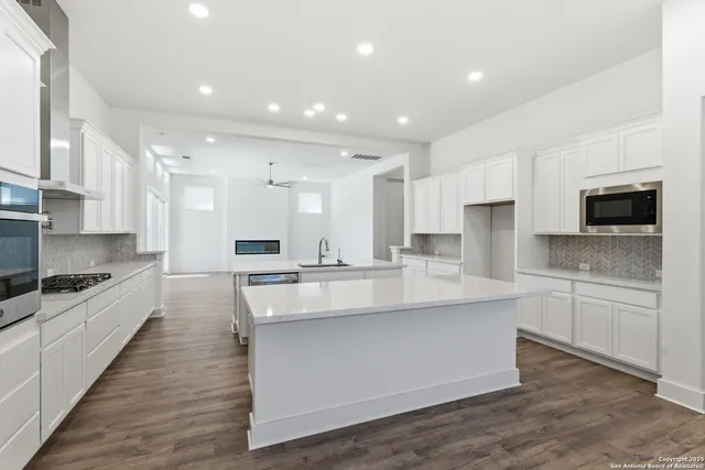 a large kitchen with stainless steel appliances lots of counter space and wooden floor