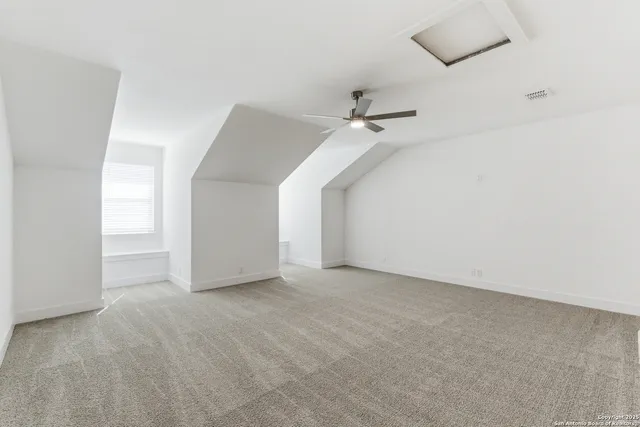 an empty room with a ceiling fan and carpet