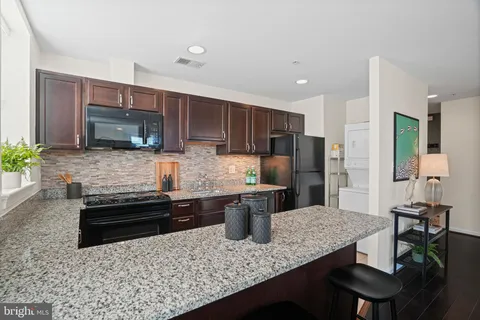 a kitchen with stainless steel appliances granite countertop a stove a sink a microwave a refrigerator and cabinets