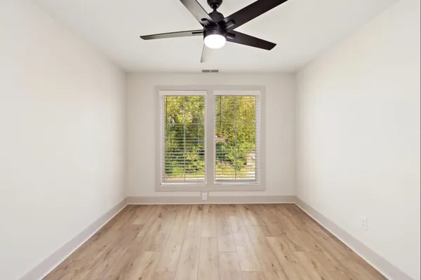 an empty room with a window and a ceiling fan