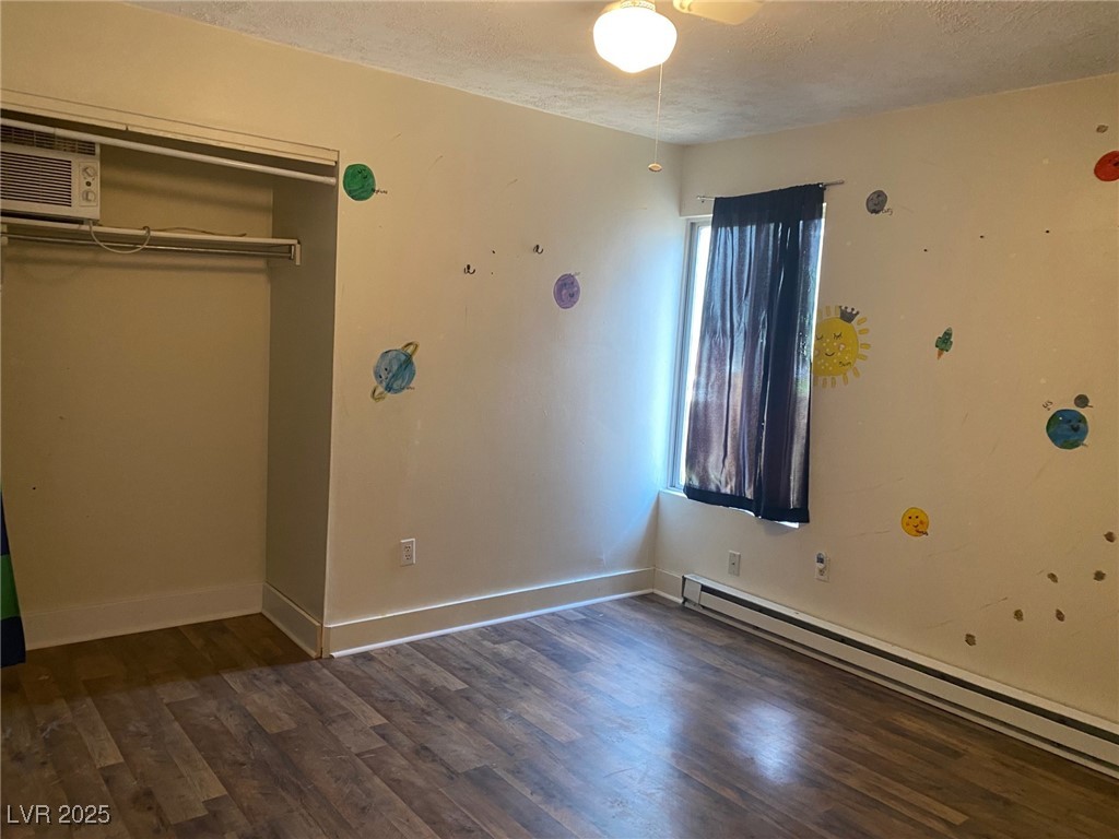1001 Mill Street Ely, NV 89301 - Photo 11 of 18 Unfurnished bedroom with a baseboard heating unit, wood finished floors, a closet, and a textured ceiling
