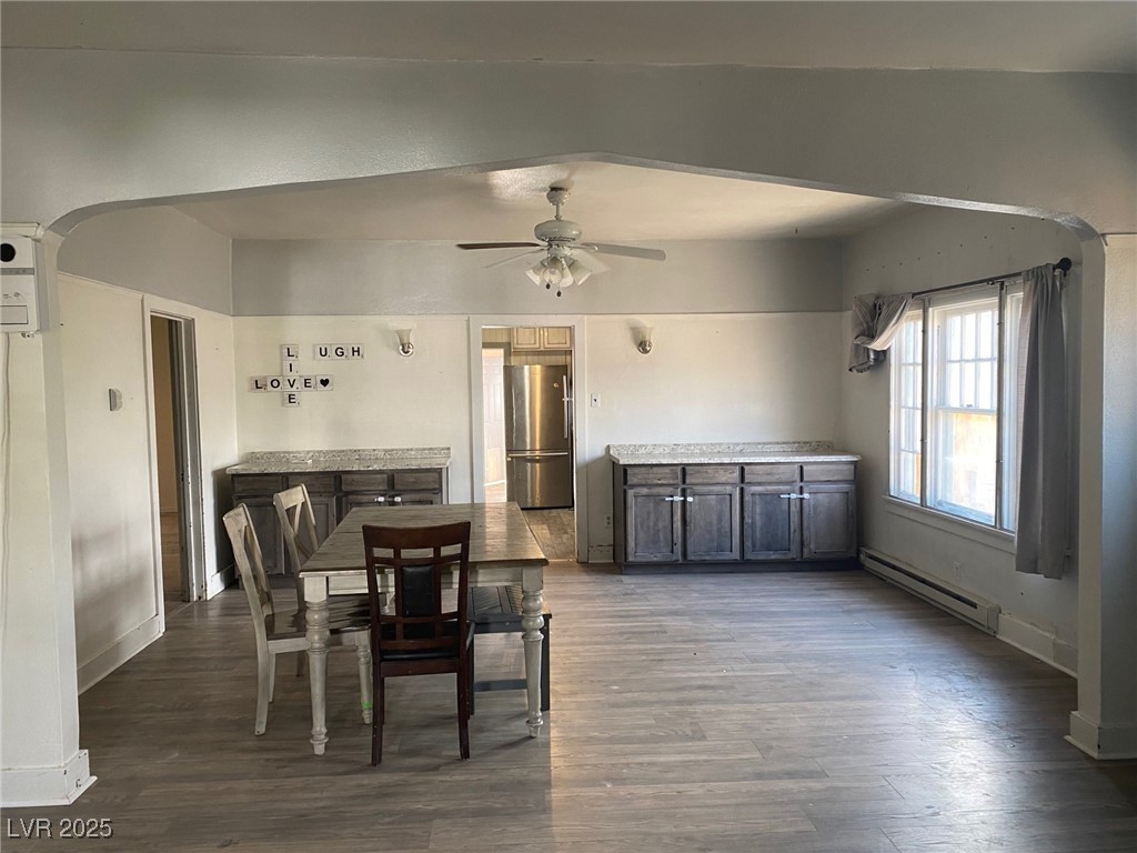 1001 Mill Street Ely, NV 89301 - Photo 3 of 18 Dining space featuring baseboard heating, wood finished floors, ceiling fan, and arched walkways