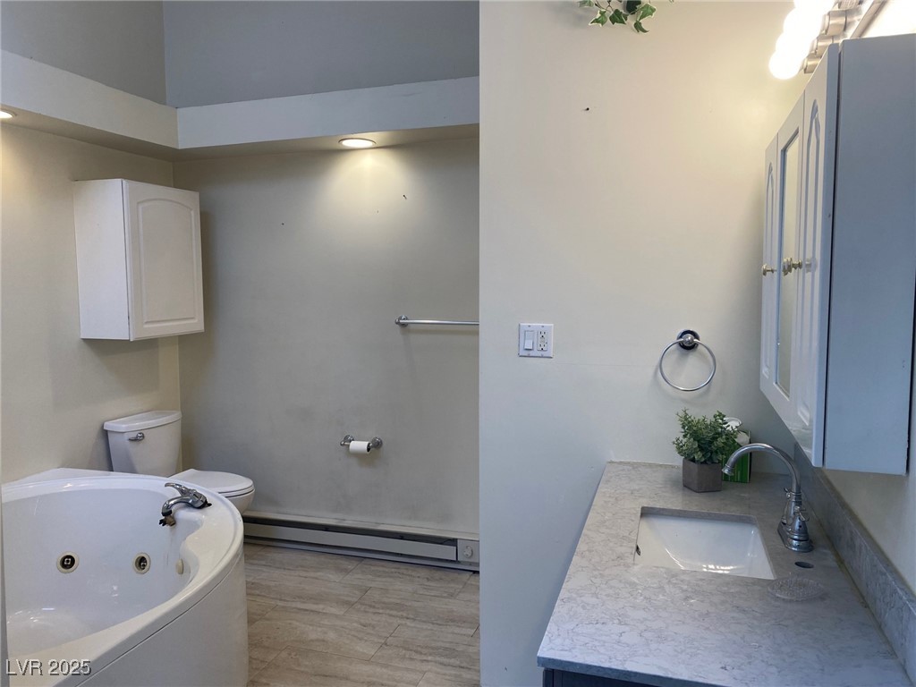 1001 Mill Street Ely, NV 89301 - Photo 9 of 18 Full bathroom featuring baseboard heating, a jetted tub, vanity, and wood finished floors