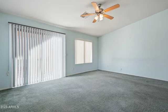 an empty room with windows and fan