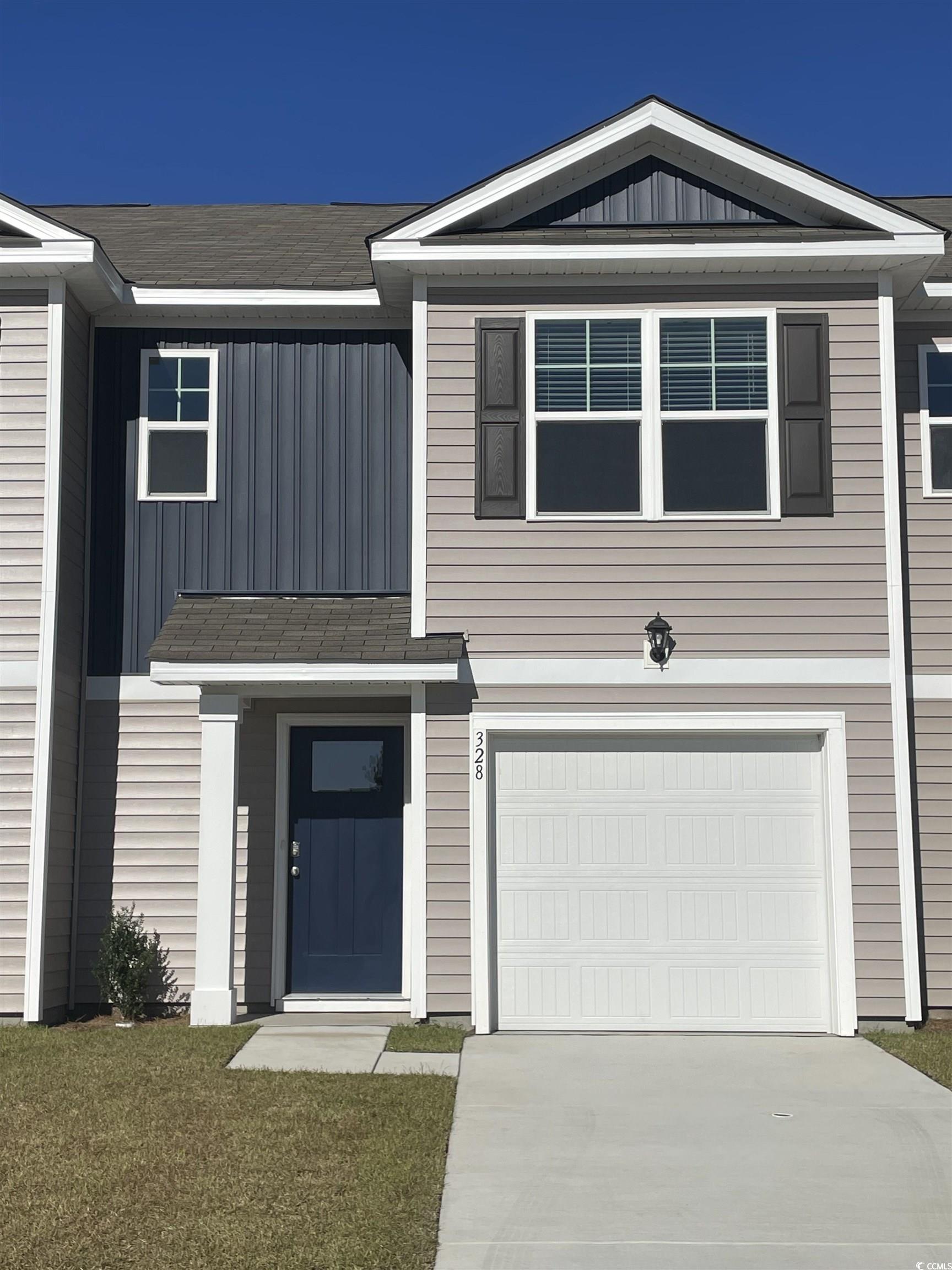 View of front of home with board and batten siding, an attached garage, concrete driveway, and a front lawn