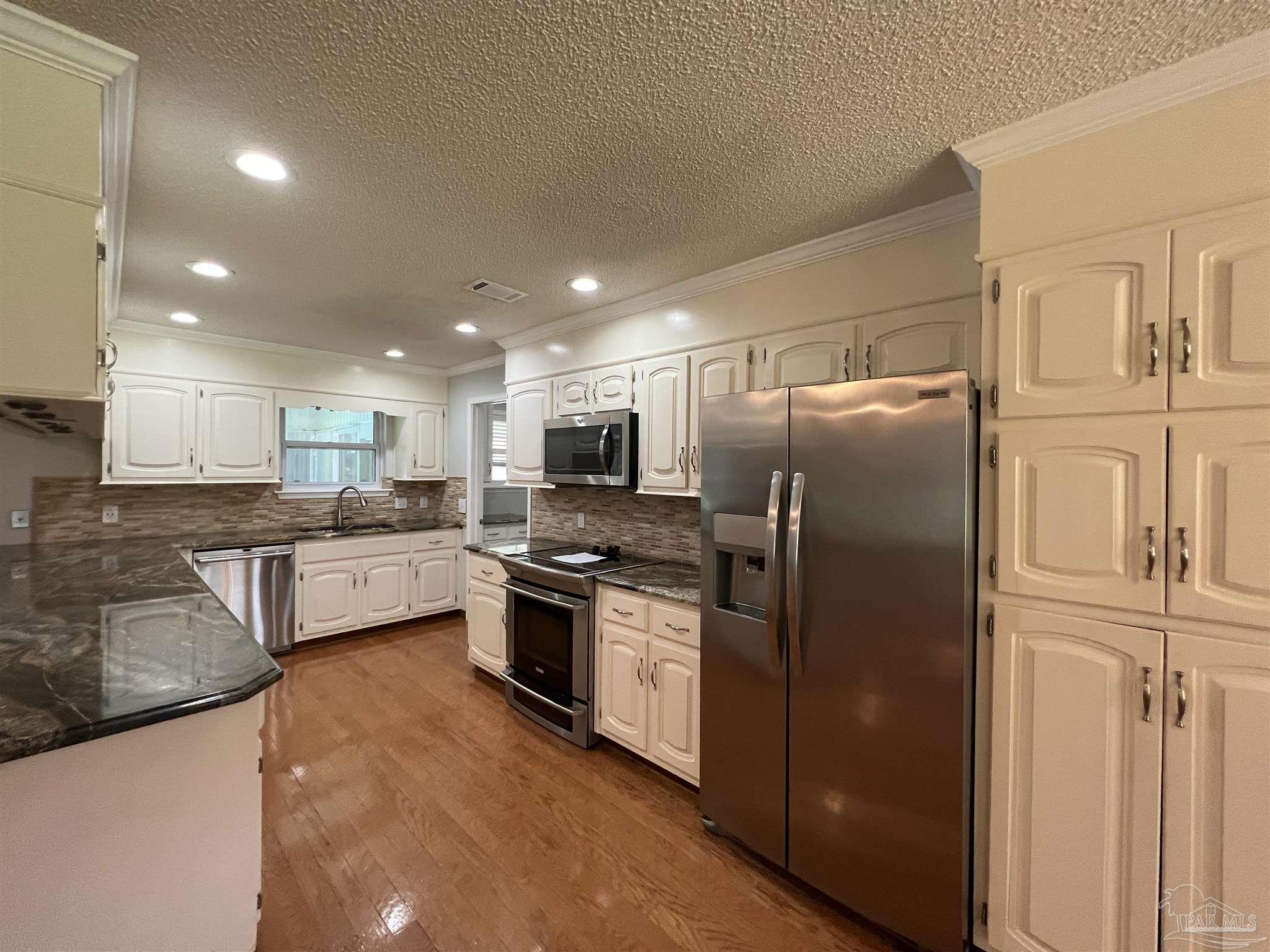 3143 Aarons Way Pace, FL 32571 - Photo 12 of 38 a kitchen with stainless steel appliances granite countertop a refrigerator a stove and a sink