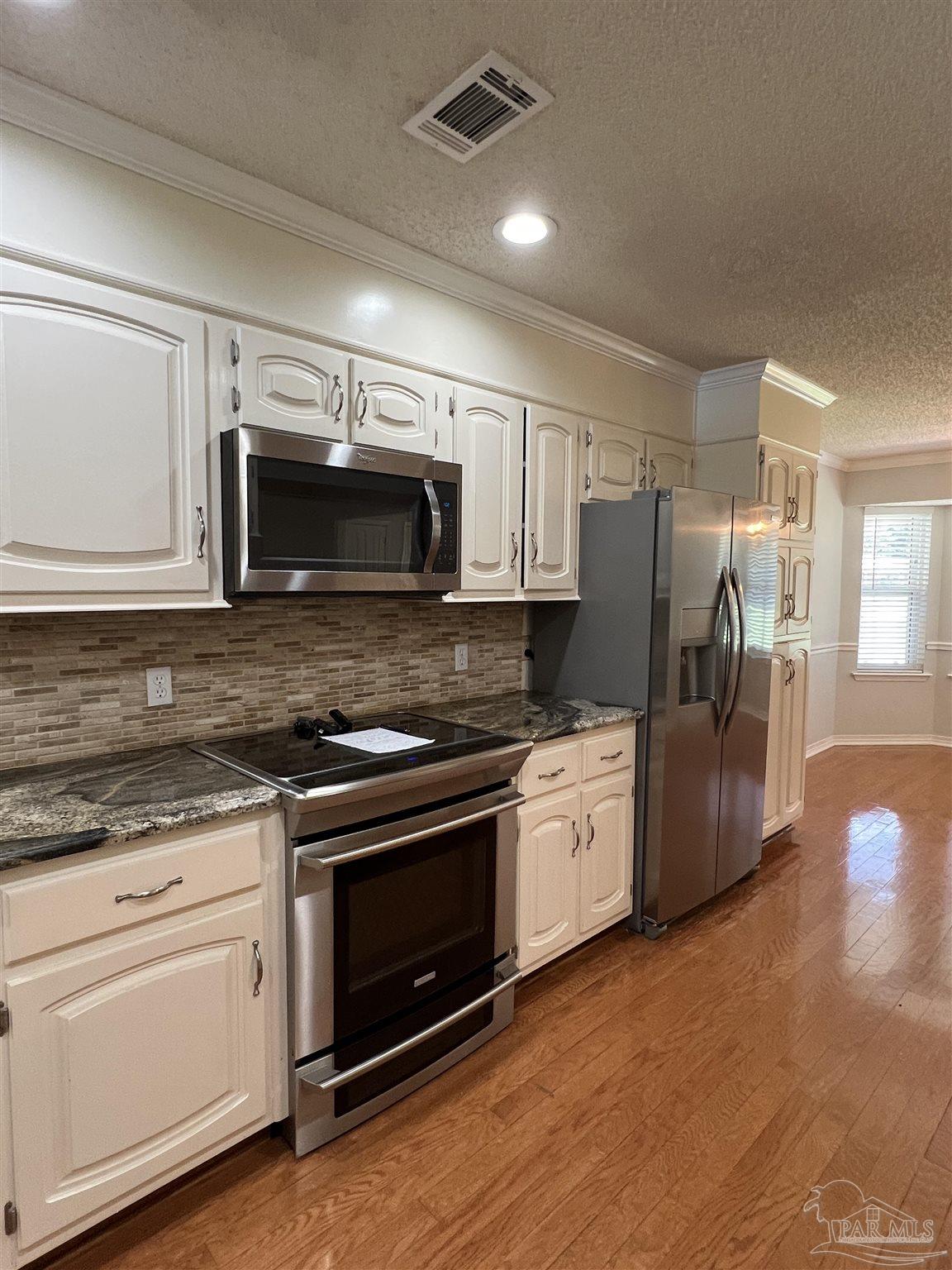 3143 Aarons Way Pace, FL 32571 - Photo 14 of 38 a kitchen with granite countertop white cabinets and stainless steel appliances