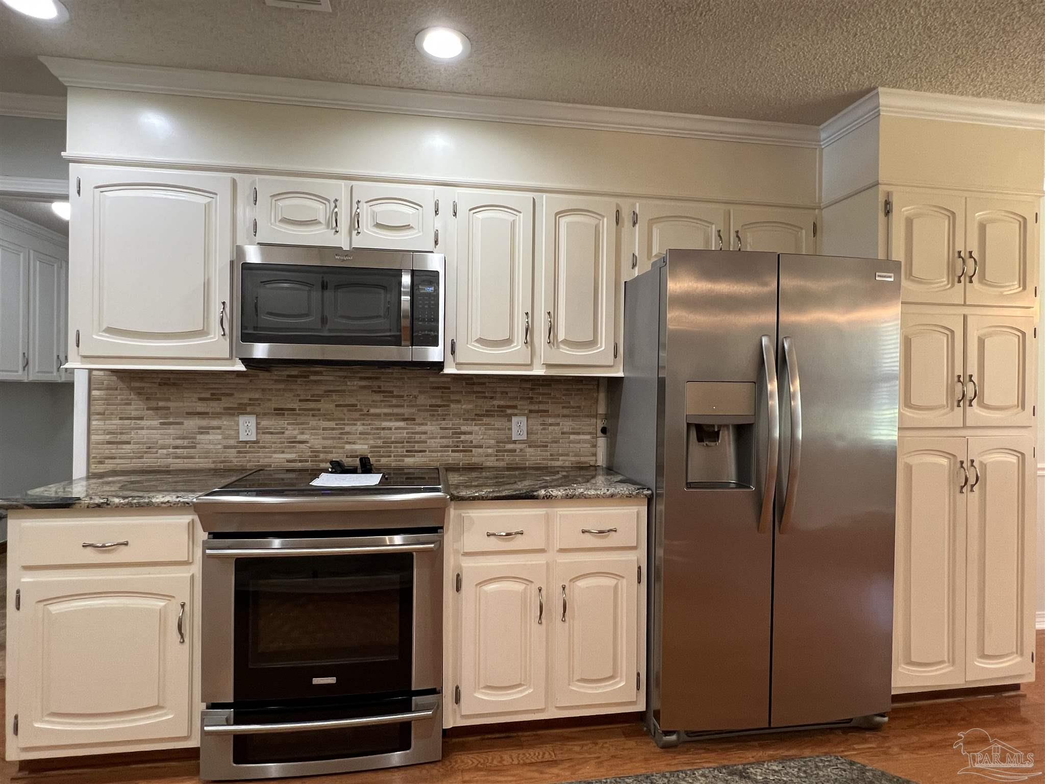 3143 Aarons Way Pace, FL 32571 - Photo 15 of 38 a kitchen with cabinets stainless steel appliances and a wooden floor