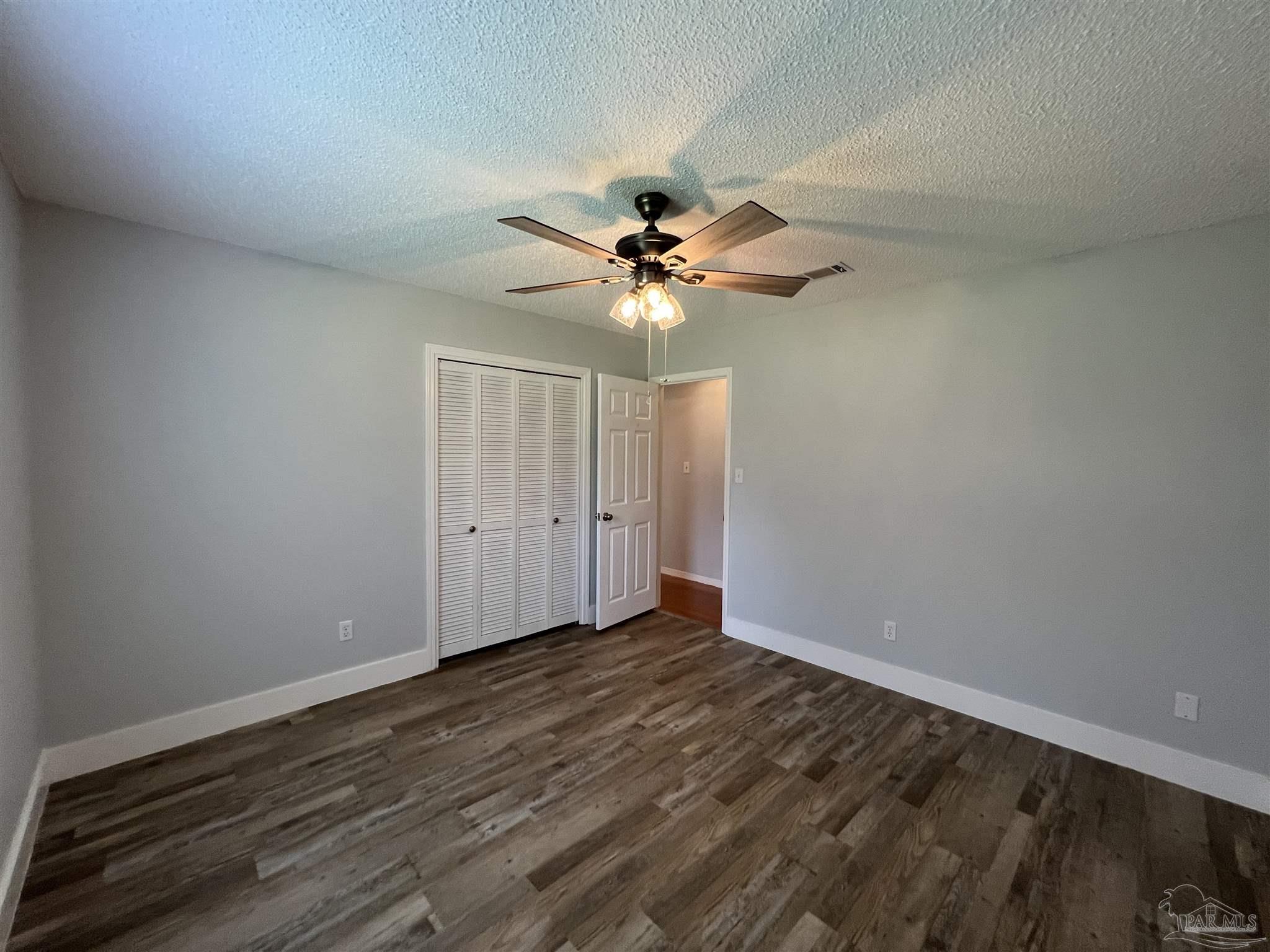 3143 Aarons Way Pace, FL 32571 - Photo 30 of 38 a view of an empty room with chandelier fan and wooden floor