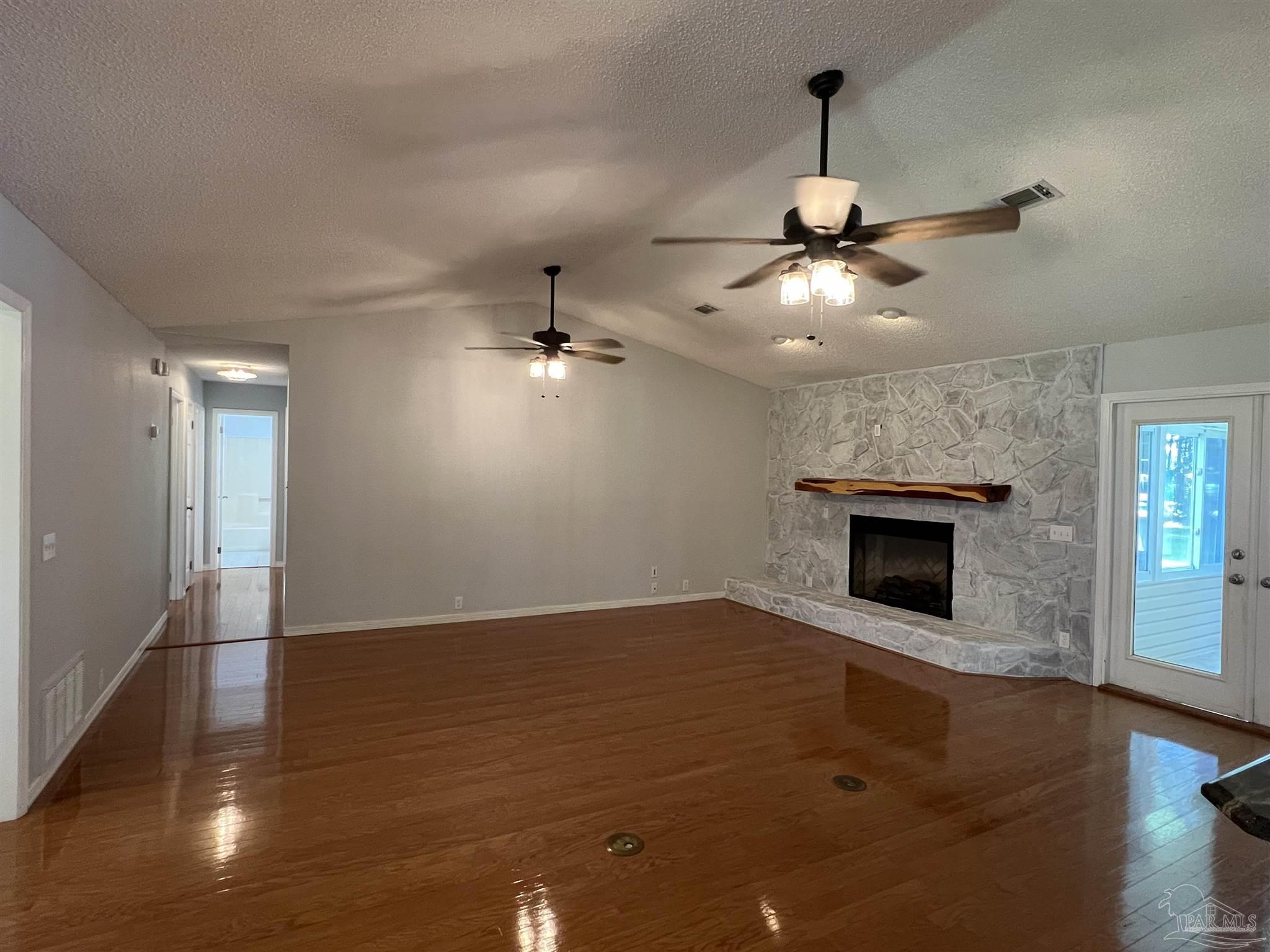 3143 Aarons Way Pace, FL 32571 - Photo 10 of 38 a view of an empty room with wooden floor fireplace and a window