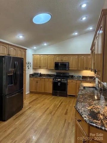 a kitchen with stainless steel appliances granite countertop a stove and a wooden floors