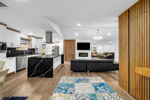 a living room with stainless steel appliances furniture and a view of kitchen