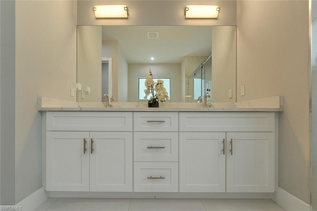 2330 4th Avenue Southeast Naples, FL 34117 - Photo 26 of 39 Bathroom featuring light tile patterned floors, double vanity, and a stall shower