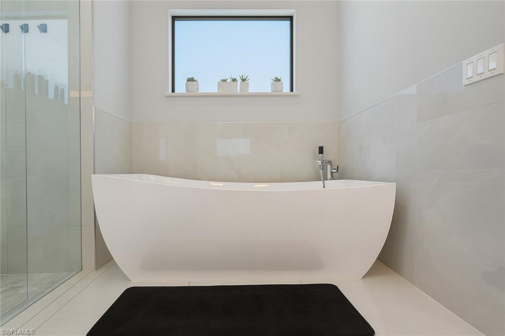 2330 4th Avenue Southeast Naples, FL 34117 - Photo 27 of 39 Full bath featuring a soaking tub, tile walls, and a shower stall