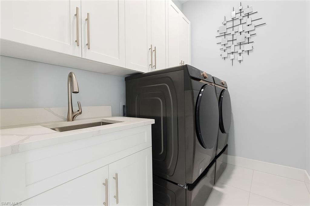 2330 4th Avenue Southeast Naples, FL 34117 - Photo 36 of 39 Laundry room featuring cabinet space, light tile patterned floors, and washing machine and clothes dryer
