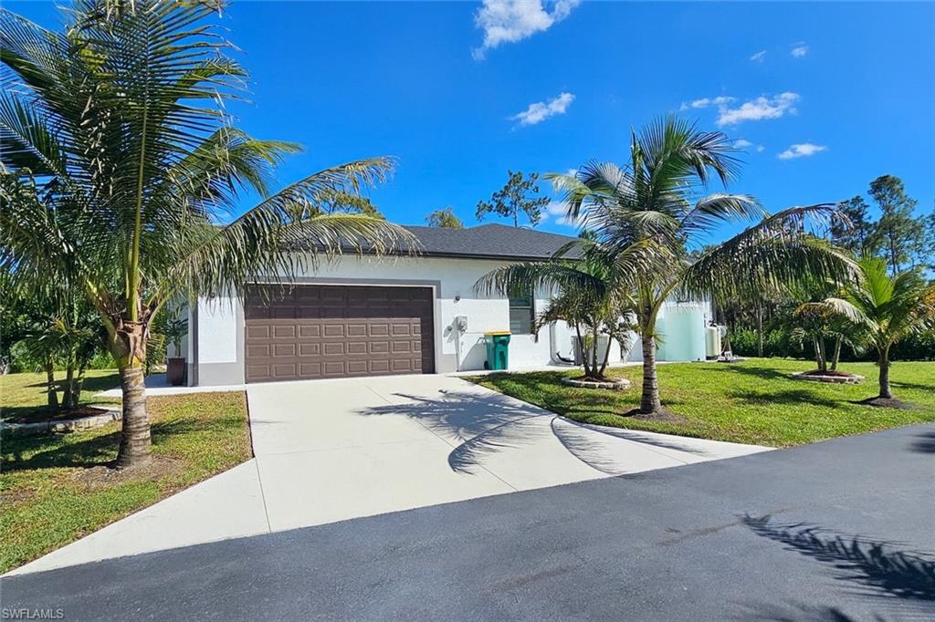 2330 4th Avenue Southeast Naples, FL 34117 - Photo 7 of 39 View of front facade with stucco siding, a front lawn, concrete driveway, and an attached garage