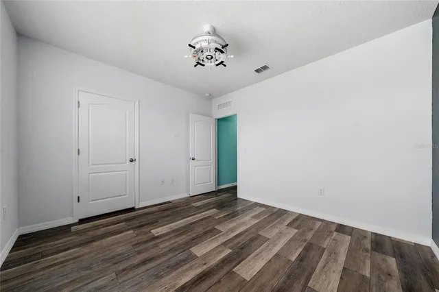 a view of a room with wooden floor and a ceiling fan