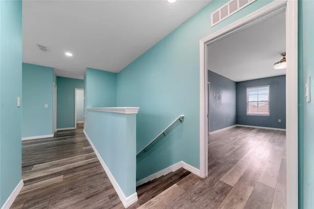 a view of a hallway with wooden floor and staircase