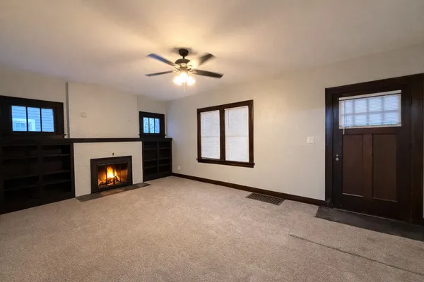 a view of an empty room with window and fire place