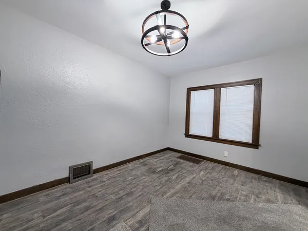 a view of an empty room with window and wooden floor