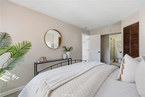 a bedroom with a bed a mirror and a potted plant