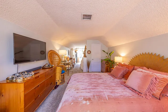a bedroom with a bed and a flat tv screen on dresser