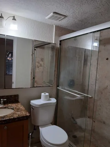 a bathroom with a granite countertop toilet sink and shower