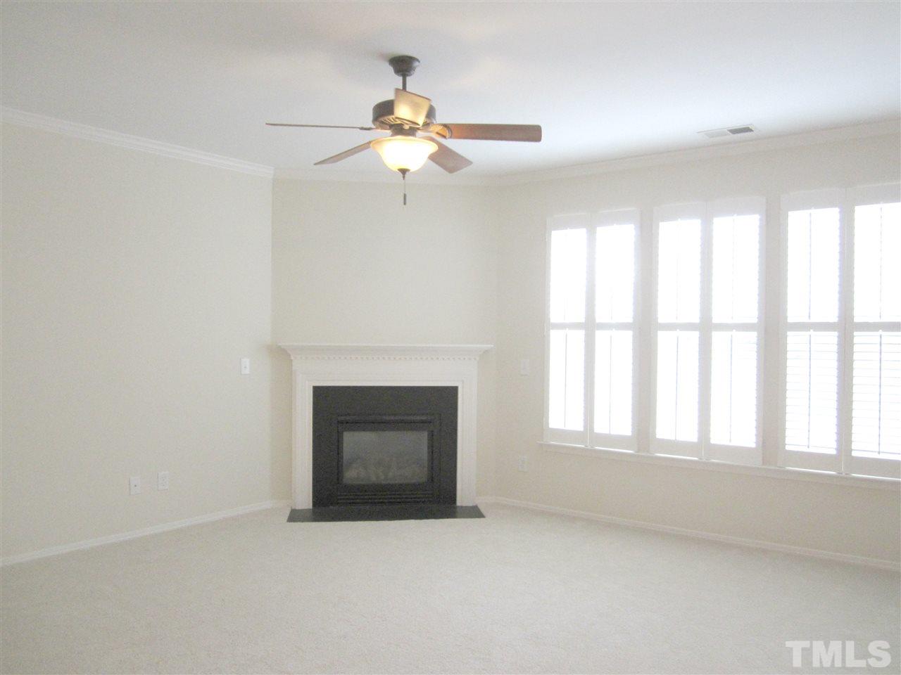8217 Beaded Stone Street Raleigh, NC 27613 - Photo 5 of 16 an empty room with windows and fireplace