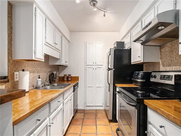 a kitchen with stainless steel appliances granite countertop a refrigerator a sink dishwasher a stove and white cabinets