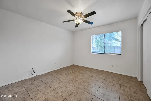 a view of an empty room with chandelier fan