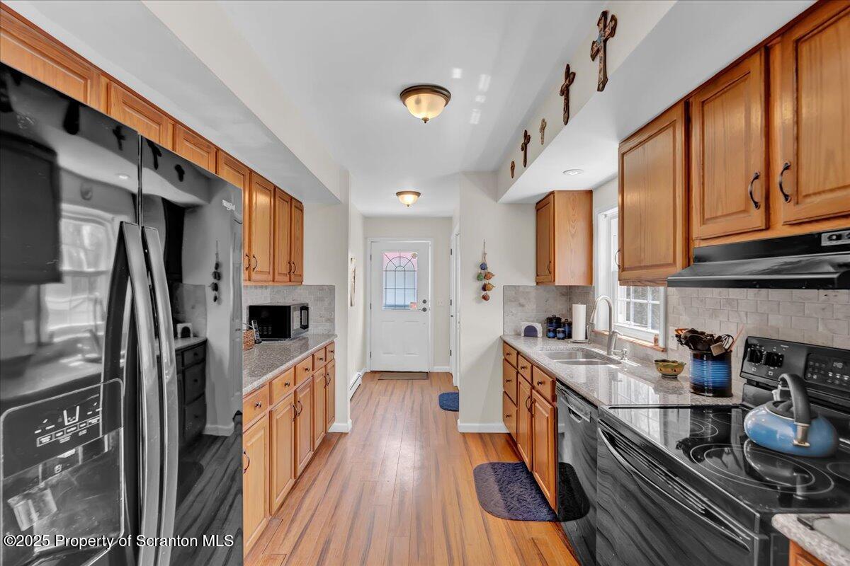 3330 Quicktown Road Moscow, PA 18444 - Photo 6 of 34 a kitchen with stainless steel appliances a stove a sink dishwasher a refrigerator white cabinets and wooden floor