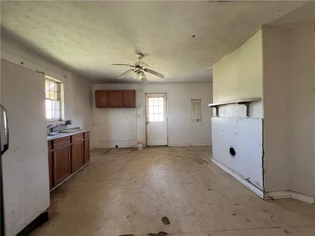 an empty room with windows and chandelier fan