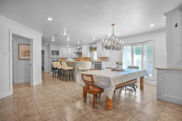 a kitchen with a dining table chairs and white cabinets