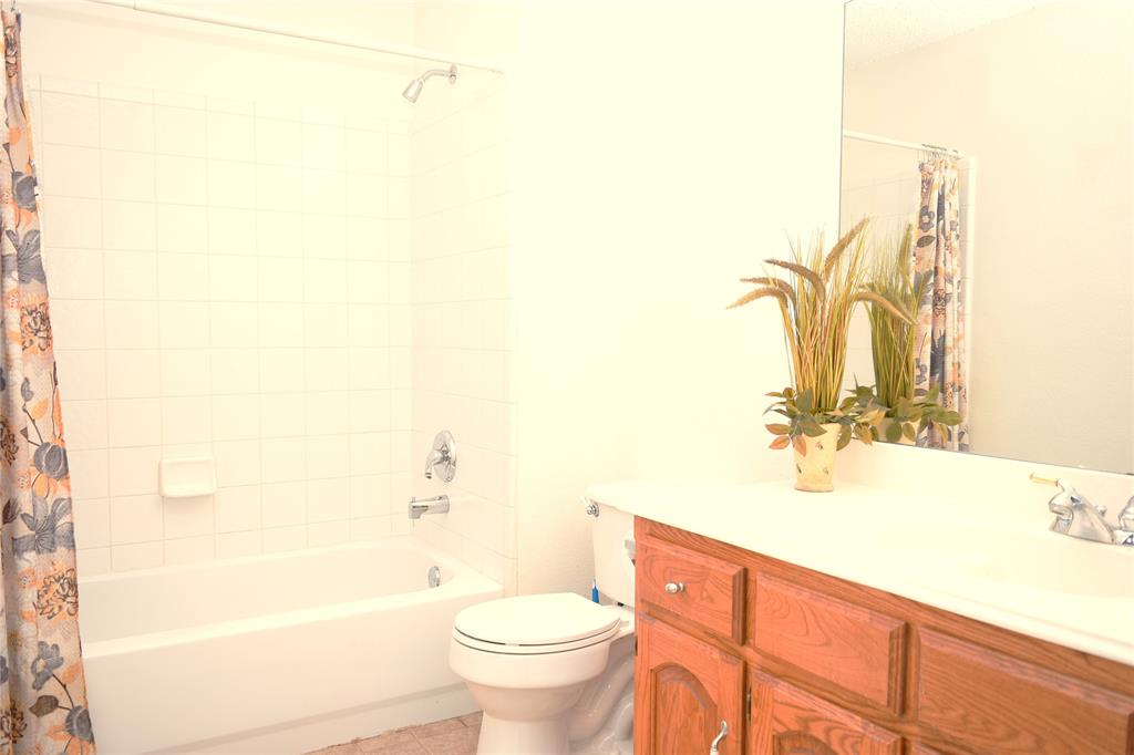 4201 Glistening Spring Rowlett, TX 75088 - Photo 25 of 33 Bathroom featuring a white bathtub with subway tile surround, white toilet, wood-finish vanity with an integrated sink, and an expansive wall-mounted mirror