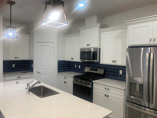 a kitchen with granite countertop a refrigerator stove and sink