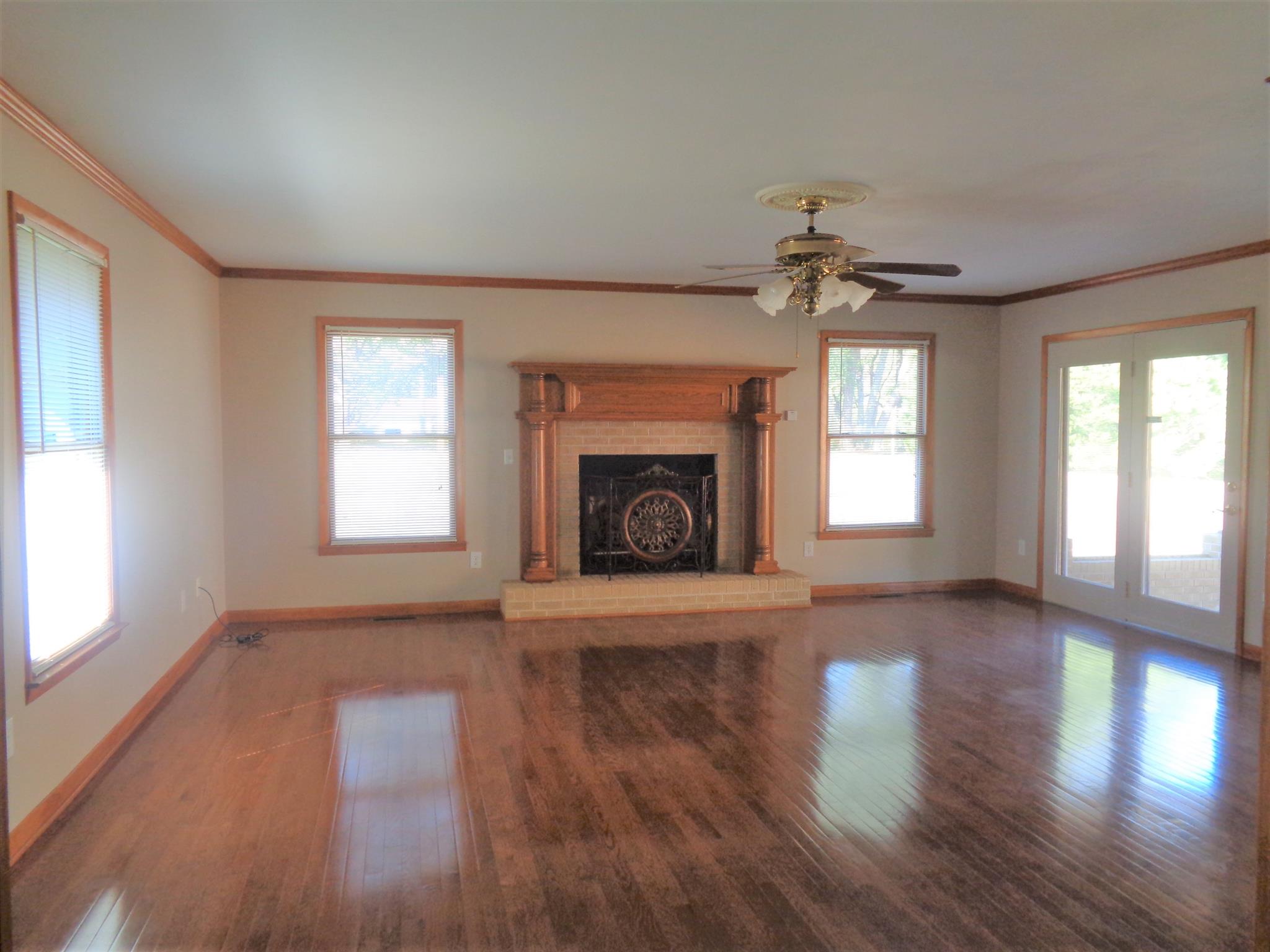 211 West Point Road Lawrenceburg, TN 38464 - Photo 3 of 25 an empty room with wooden floor fireplace and windows