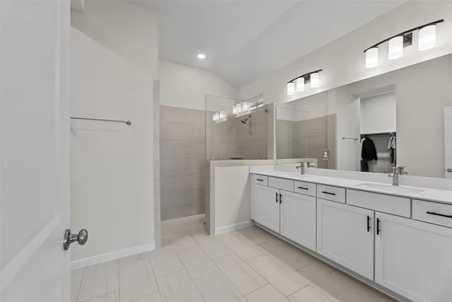 a spacious bathroom with a double vanity sink a mirror and a shower